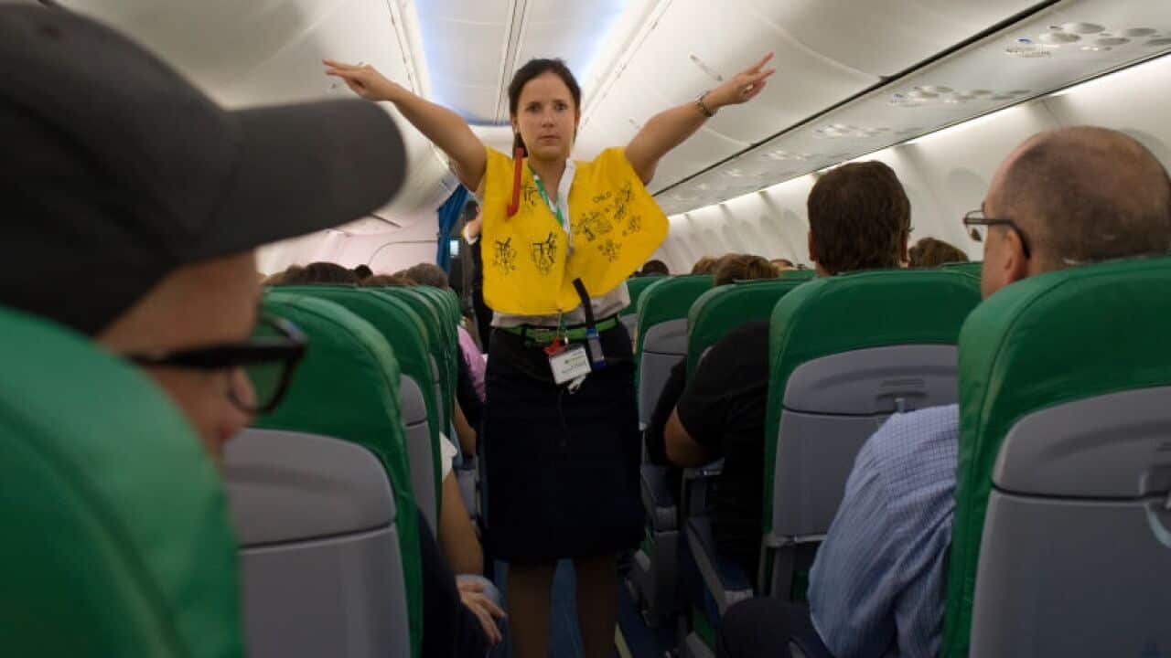 A flight attendant gives a safety demonstration