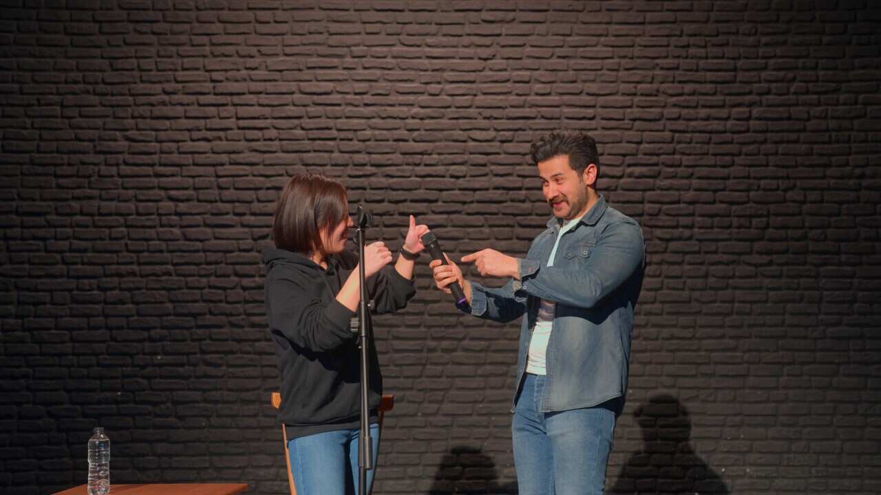 Male stand-up comedian talking on stage and inviting one of the audiences to stage