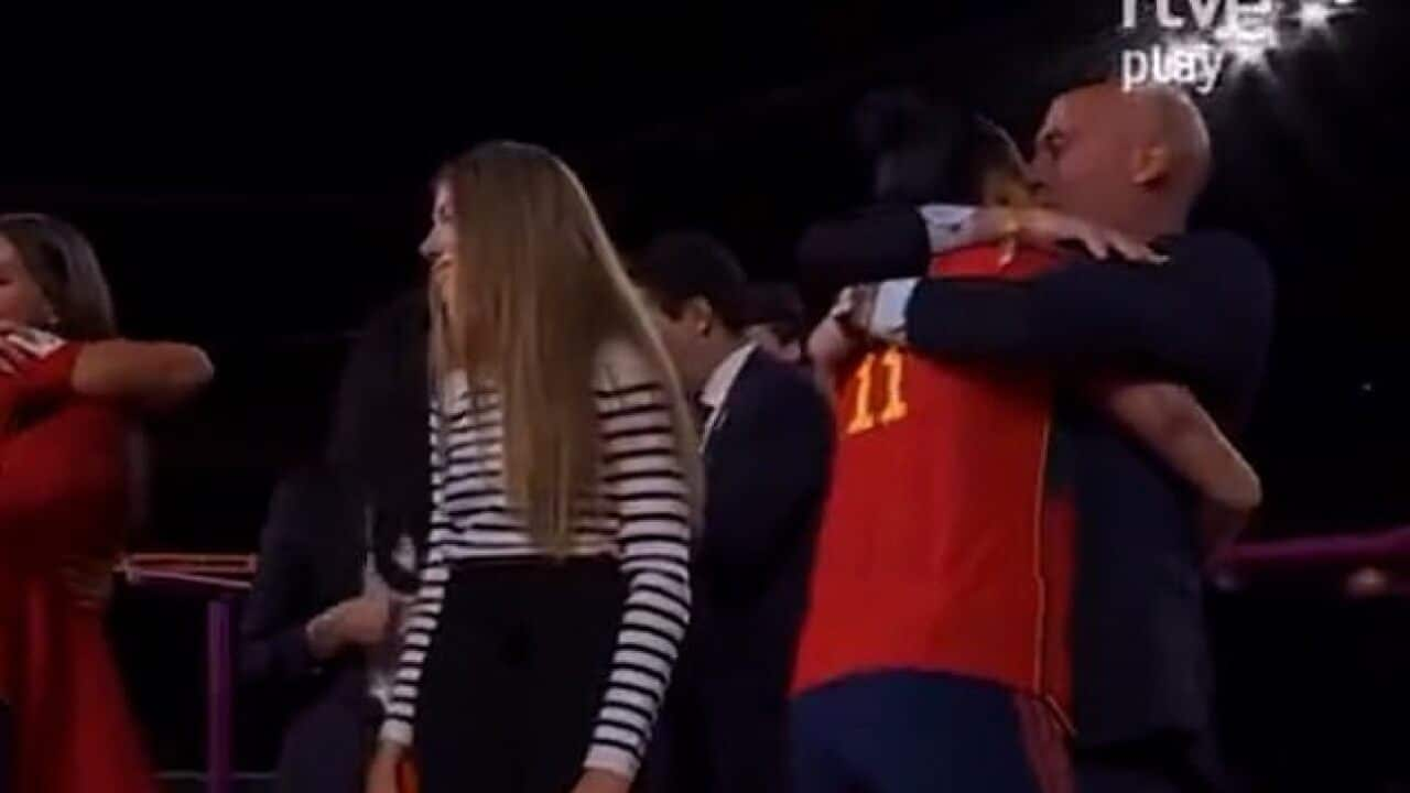 A bald man embraces a female footballer. 