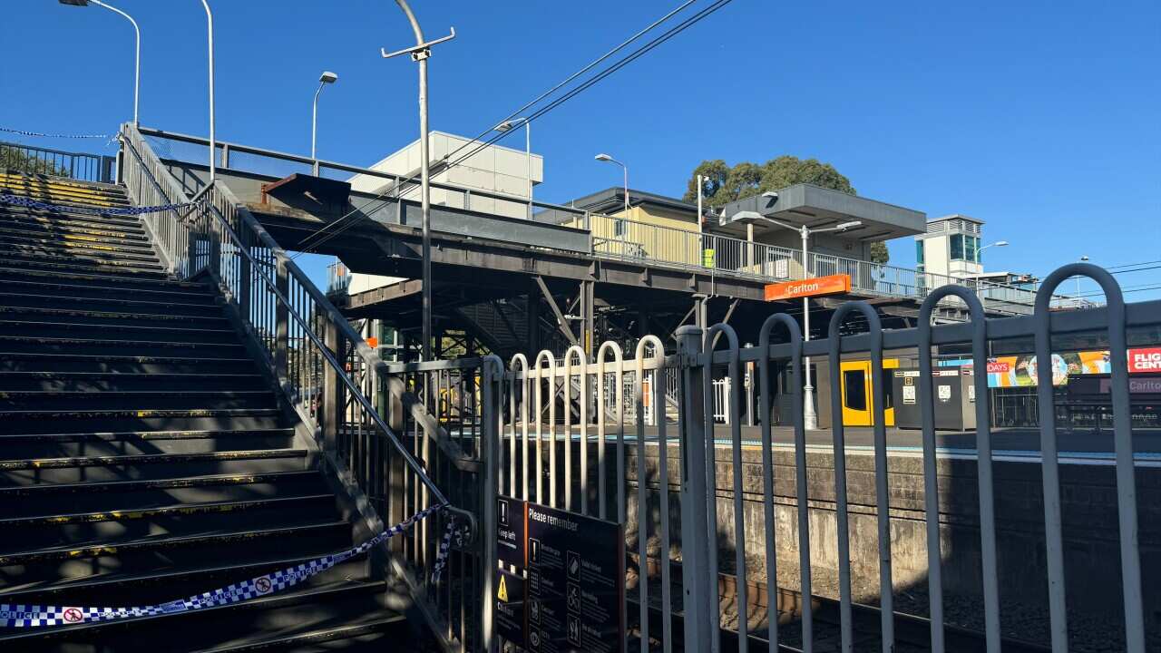 A train station with a police line blocking the stairs.