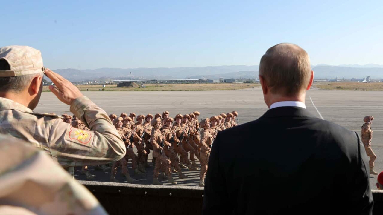 FILE: Russian President Vladimir Putin, right, watches the troops marching as he and Syrian President Bashar Assad visit the Hemeimeem air base in Syria in 2017