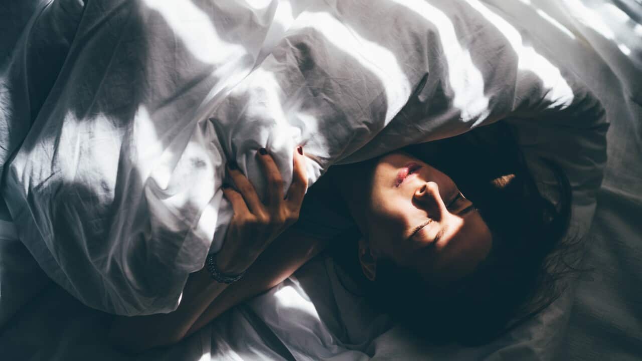 Sleepless Woman Lying In Bed Hiding Under Duvet.