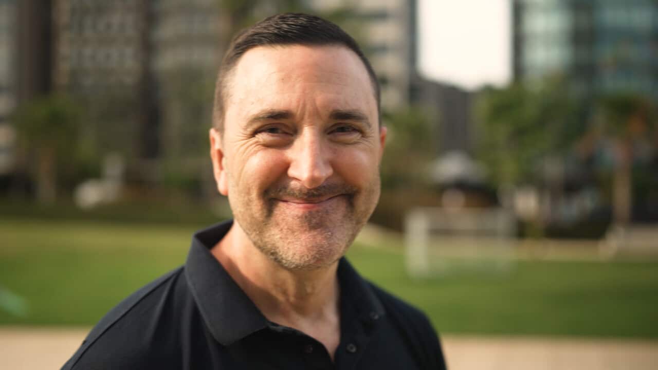A close up shot of a man with short brown hair smiling