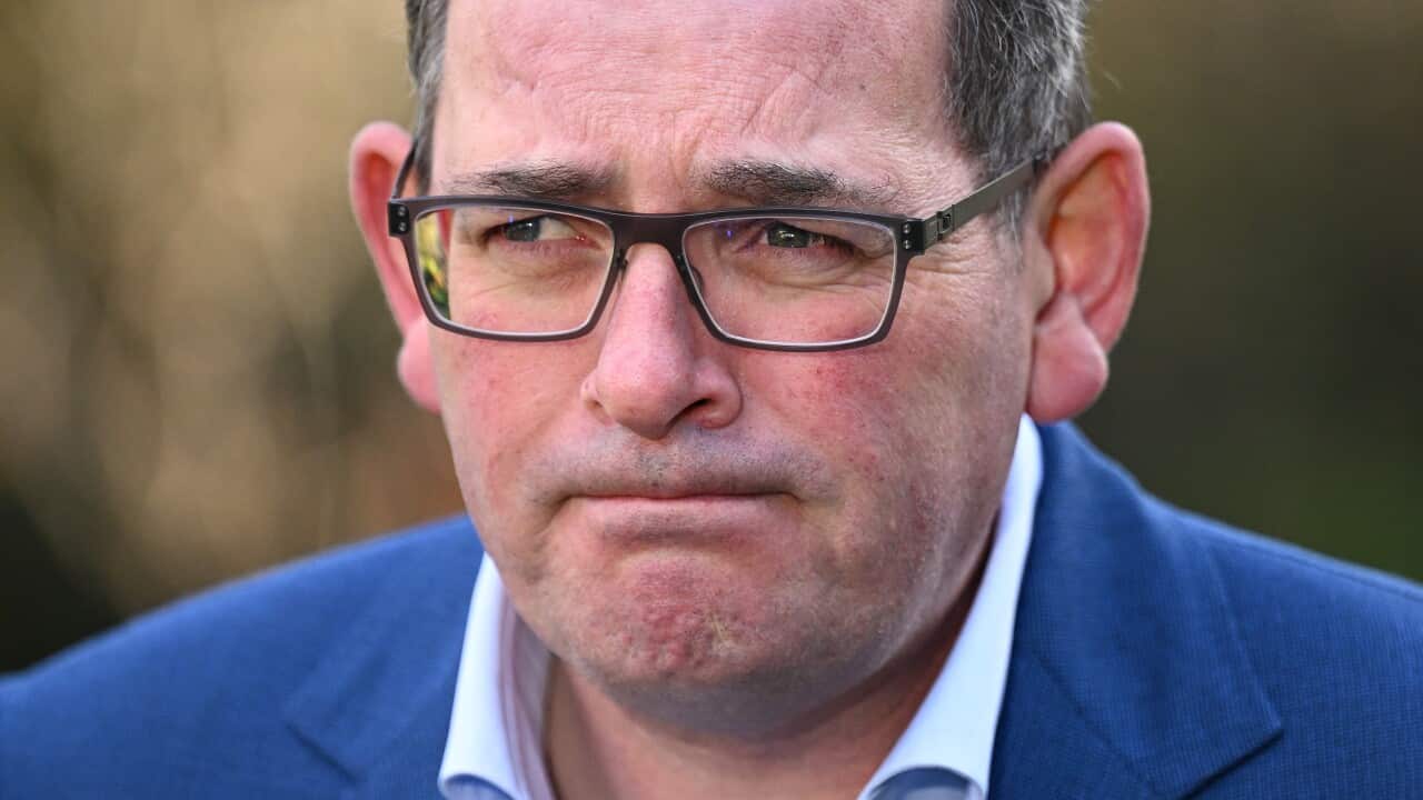 A man wearing a suit and glasses standing outside.
