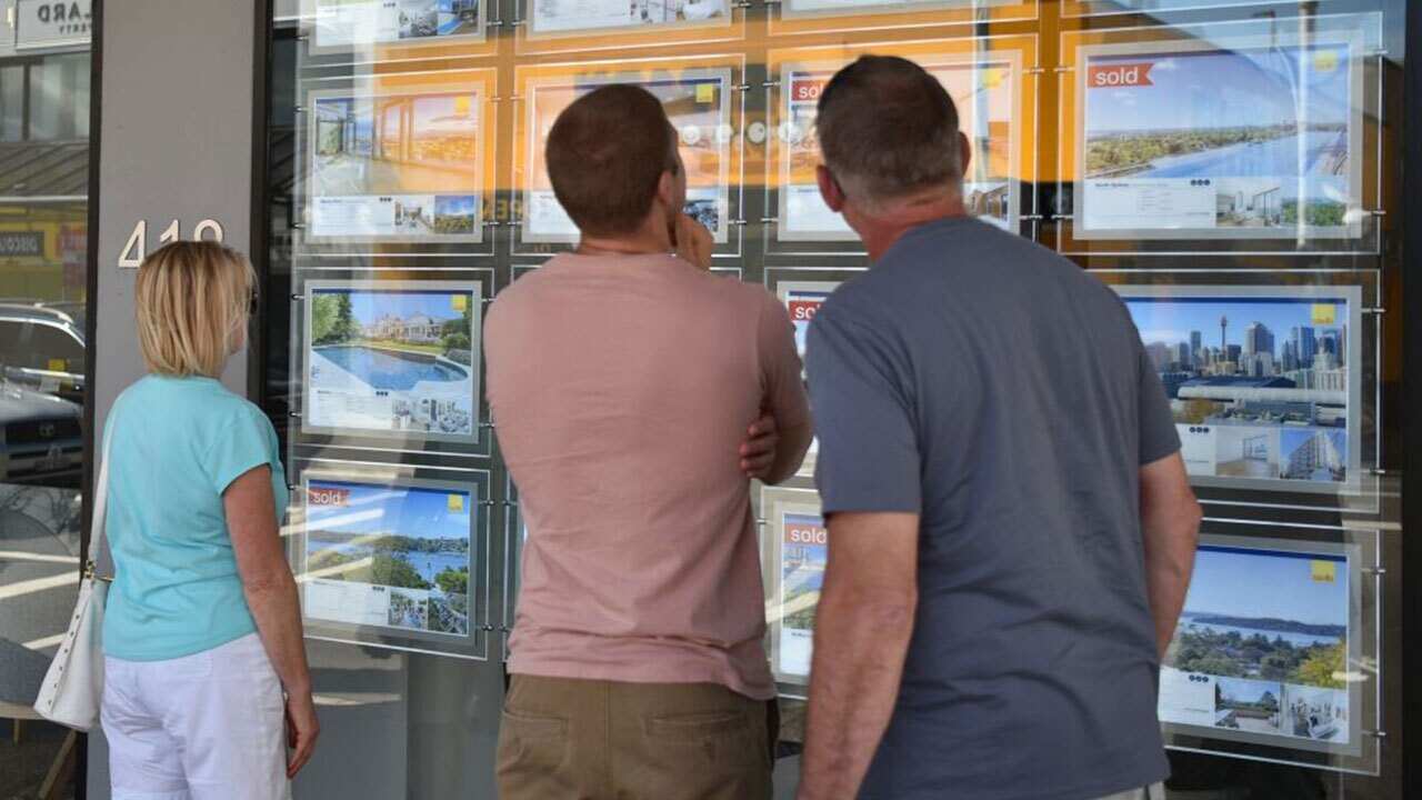 A family looks at properties for sale in a property agents window in Sydney on December 5, 2017.