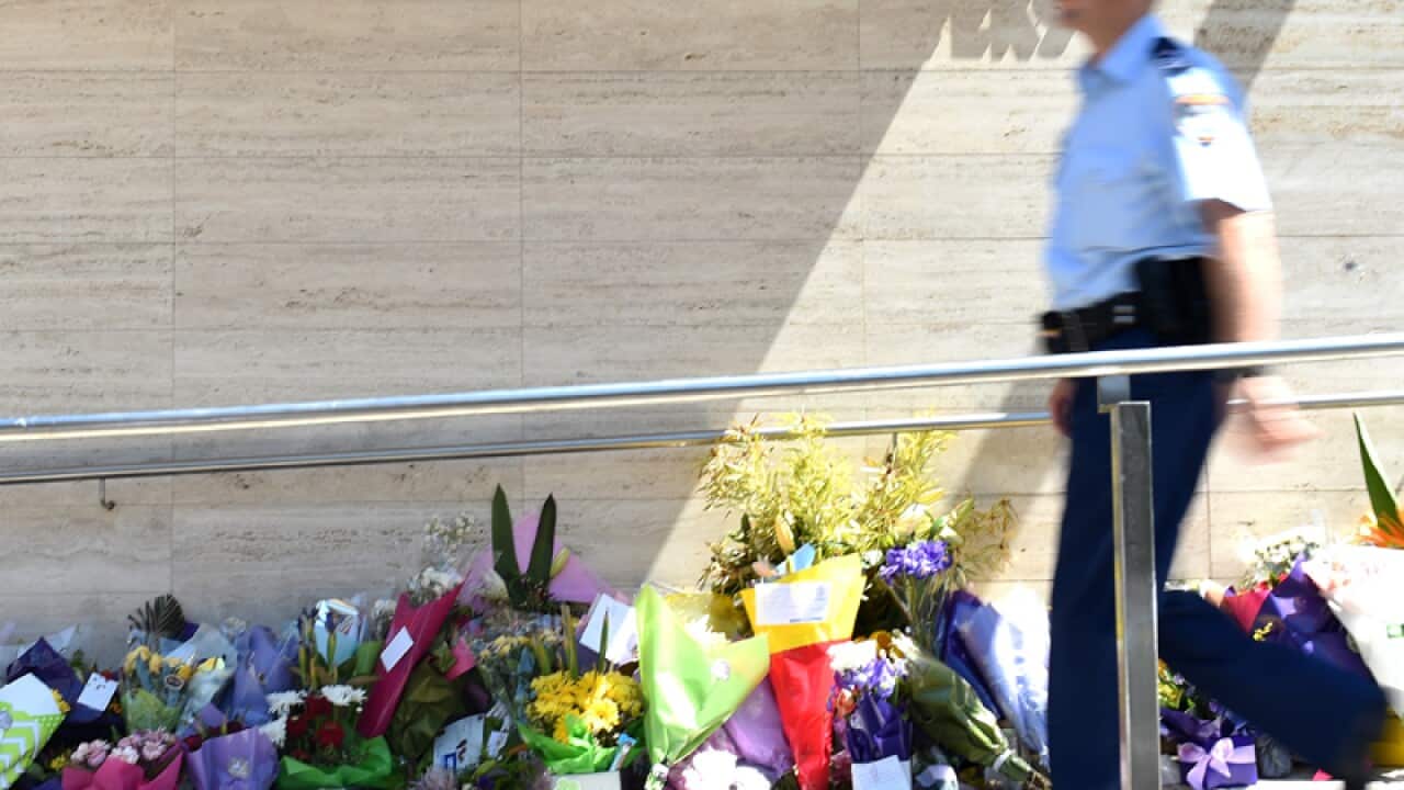 police officer passes flowers placed for police employee Curtis Cheng