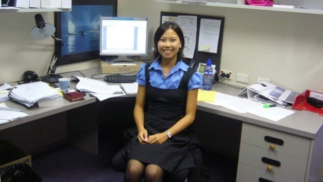 A young Asian woman smiles as she sits in her office