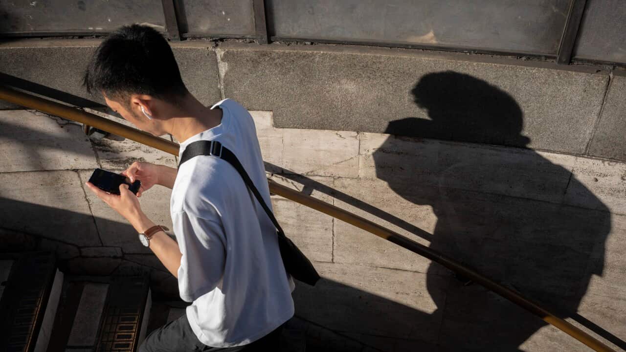 A male walking up stairs while texting on their mobile