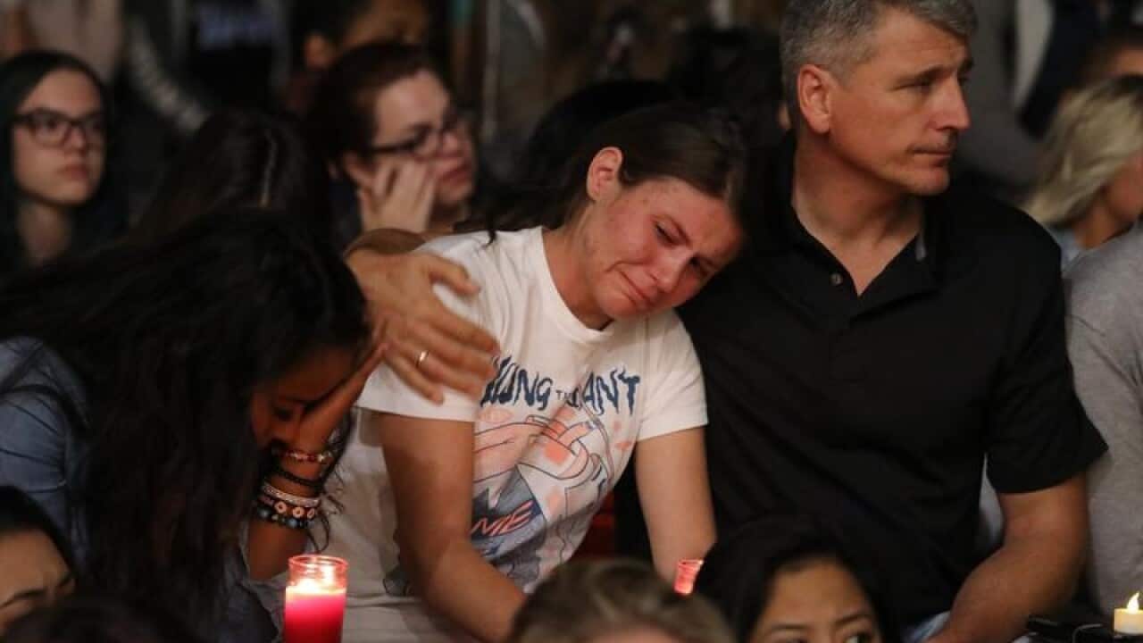 Mourners react during a candlelight vigil
