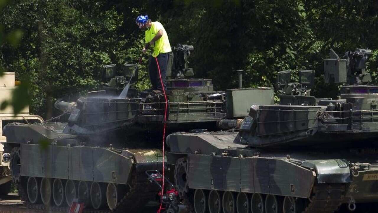 A worker washing an Abrams tank, for July 4 celebrations