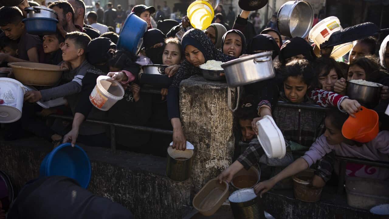 A tight crowd of people holding pots and pans