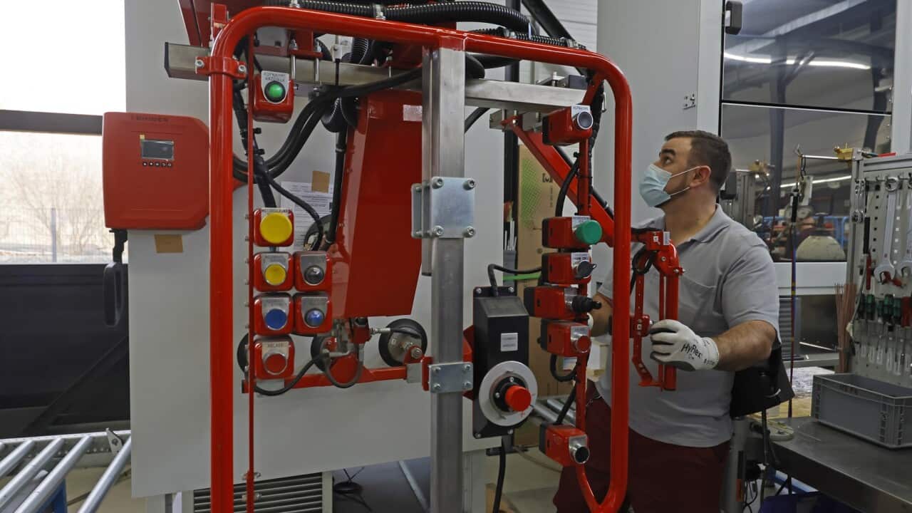 An employee works on an ultra-deep freezer required to store the COVID-19 vaccine