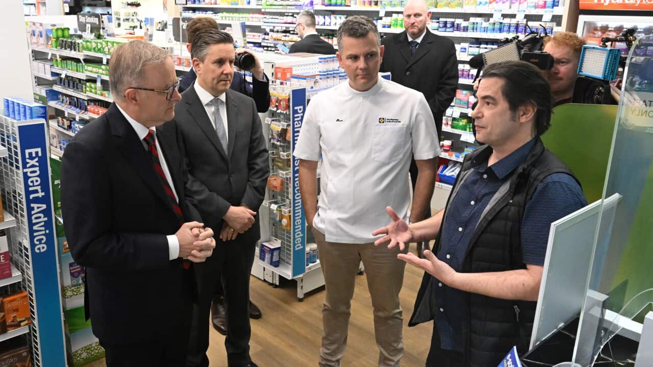 Four men talk to each other in a chemist