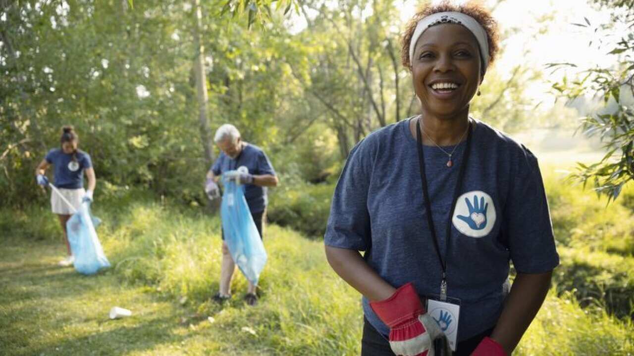 Portrait confident senior woman volunteering, cleaning up garbage in park