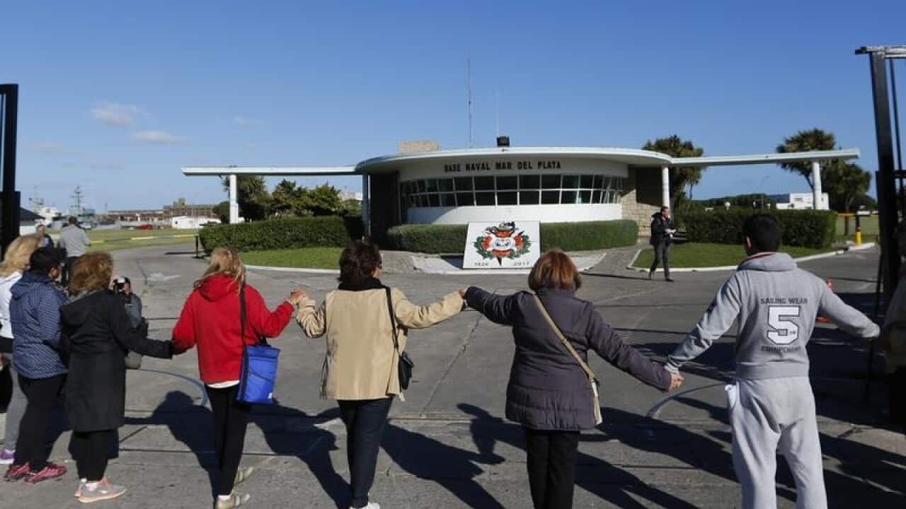 A group of people pray in support of the crew of the missing submarine