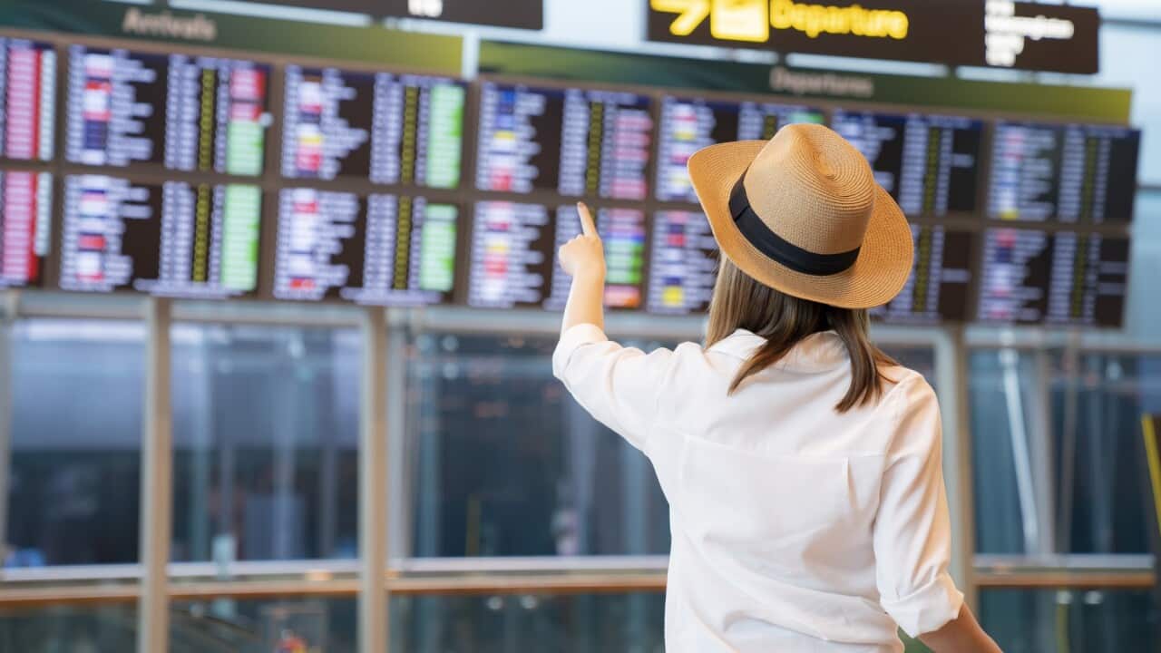 Female passenger looking flight schedule on the digital board in the terminal
