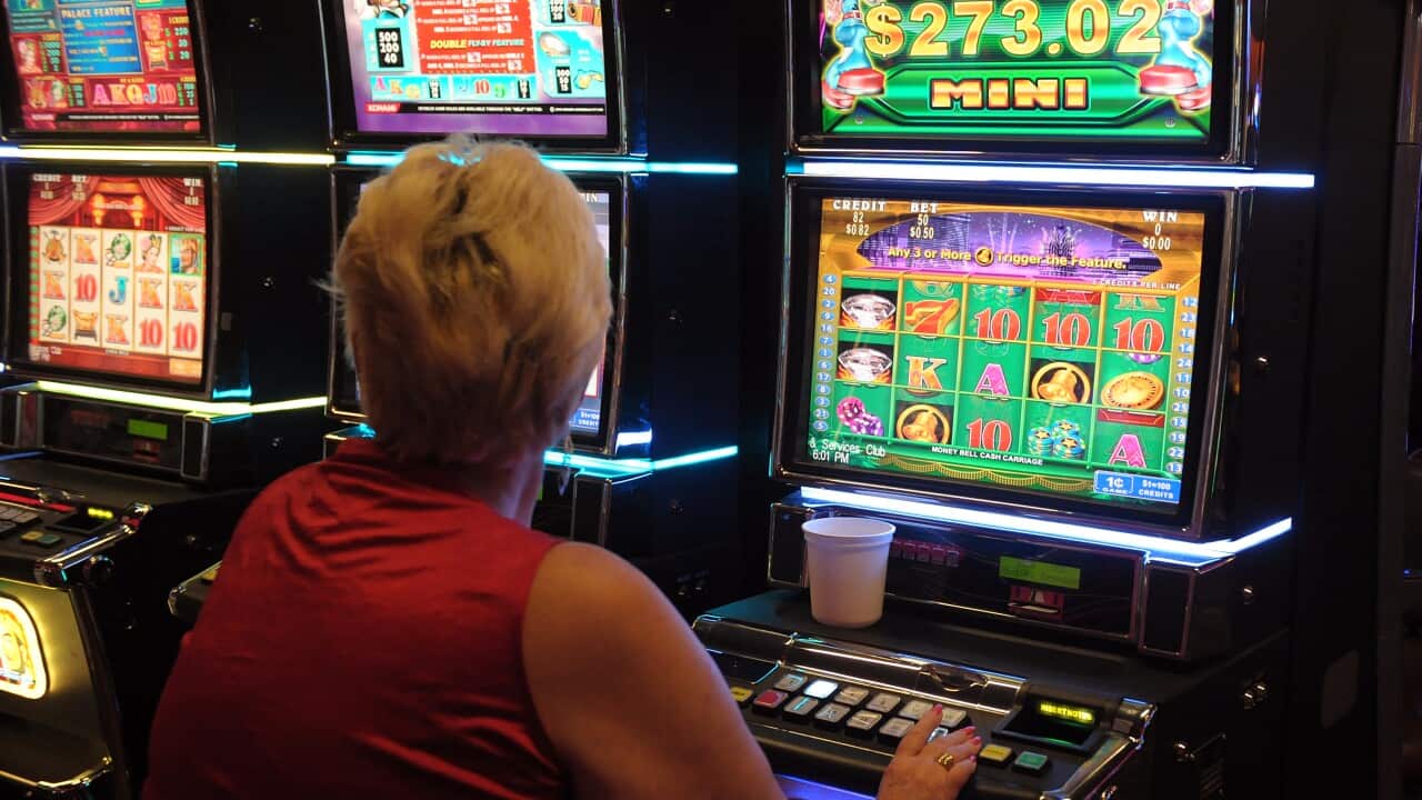 A woman hitting buttons at a fluorescent pokie machine.