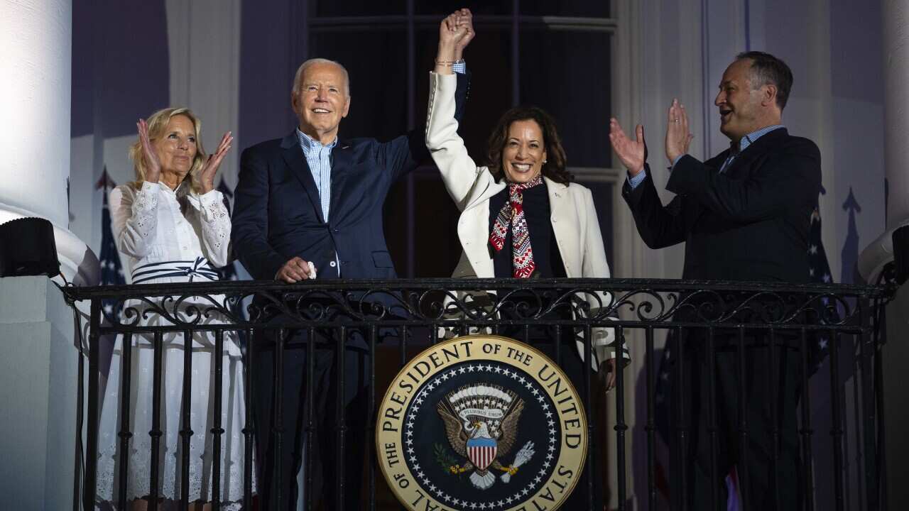 First lady Jill Biden, left, and second gentleman Douglass Emhoff, right, watch as President Joe Biden, center left, raises the hand of Vice President Kamala Harris as they view the Independence Day firework display over the National Mall from the balcony of the White House, July 4, 2024, in Washington.