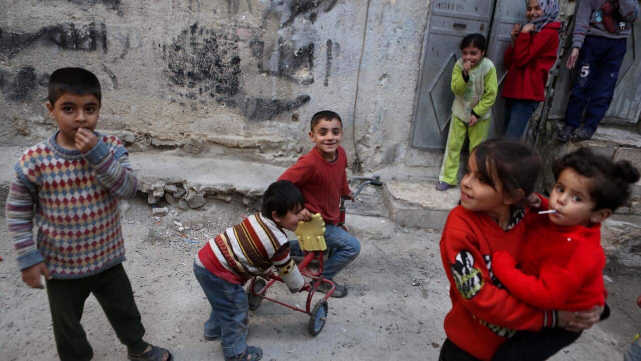 Syrian children play outside their home at the rebel-held neighborhood of Tishreen, after a ceasefire that went into effect in Damascus, Syria