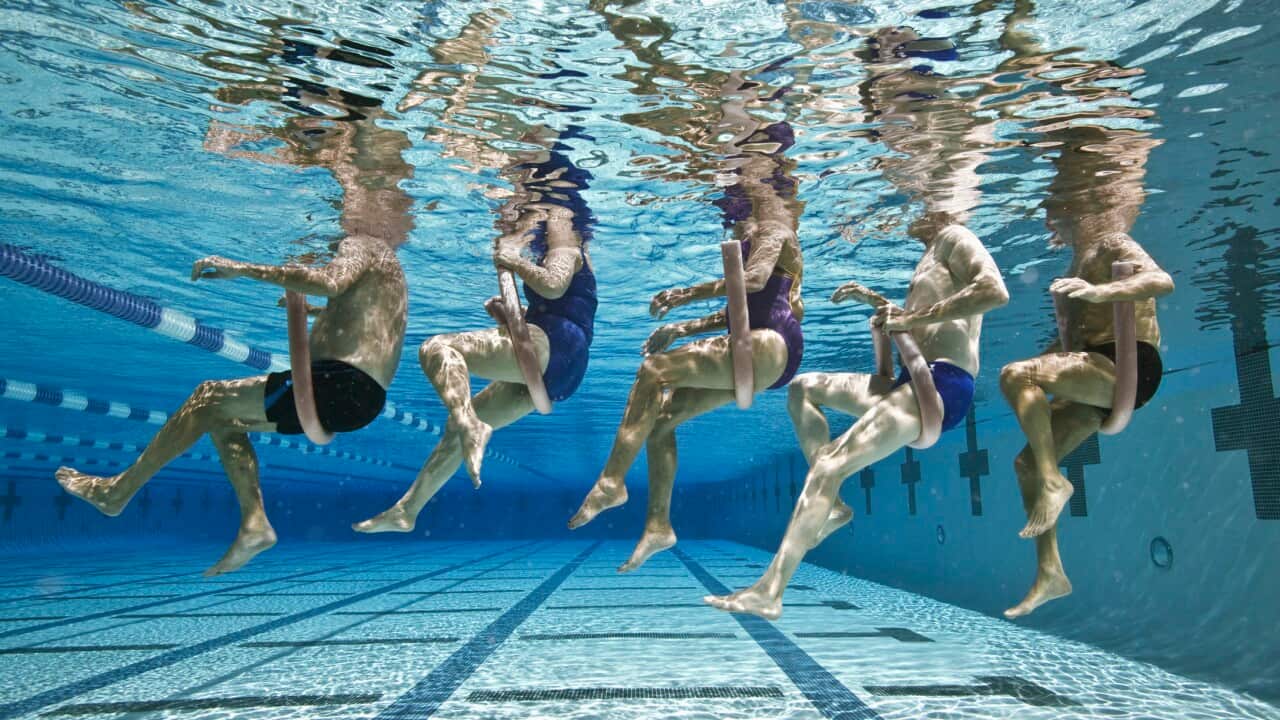 Five senior people in swimming pool, underwater, low section