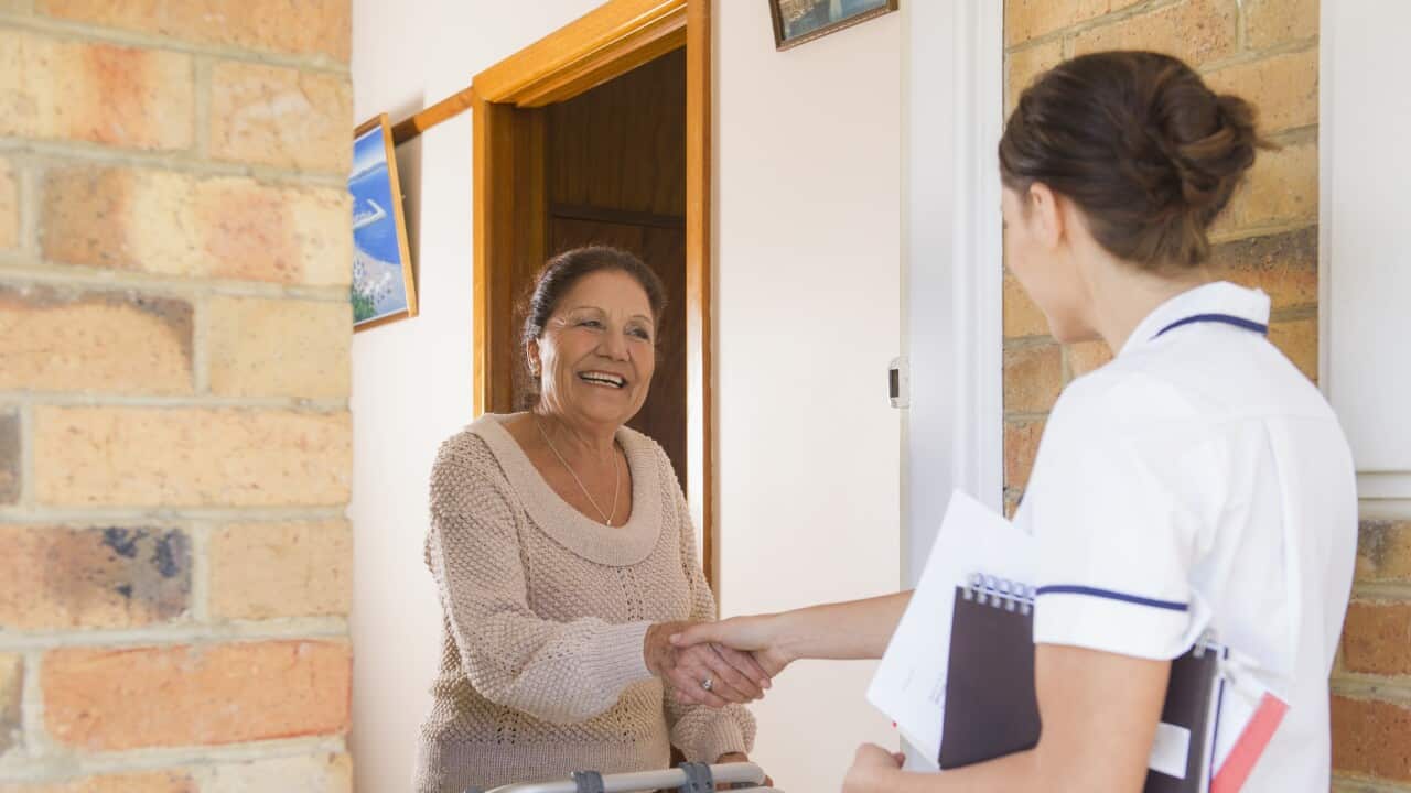 Hispanic woman greeting nurse in doorway