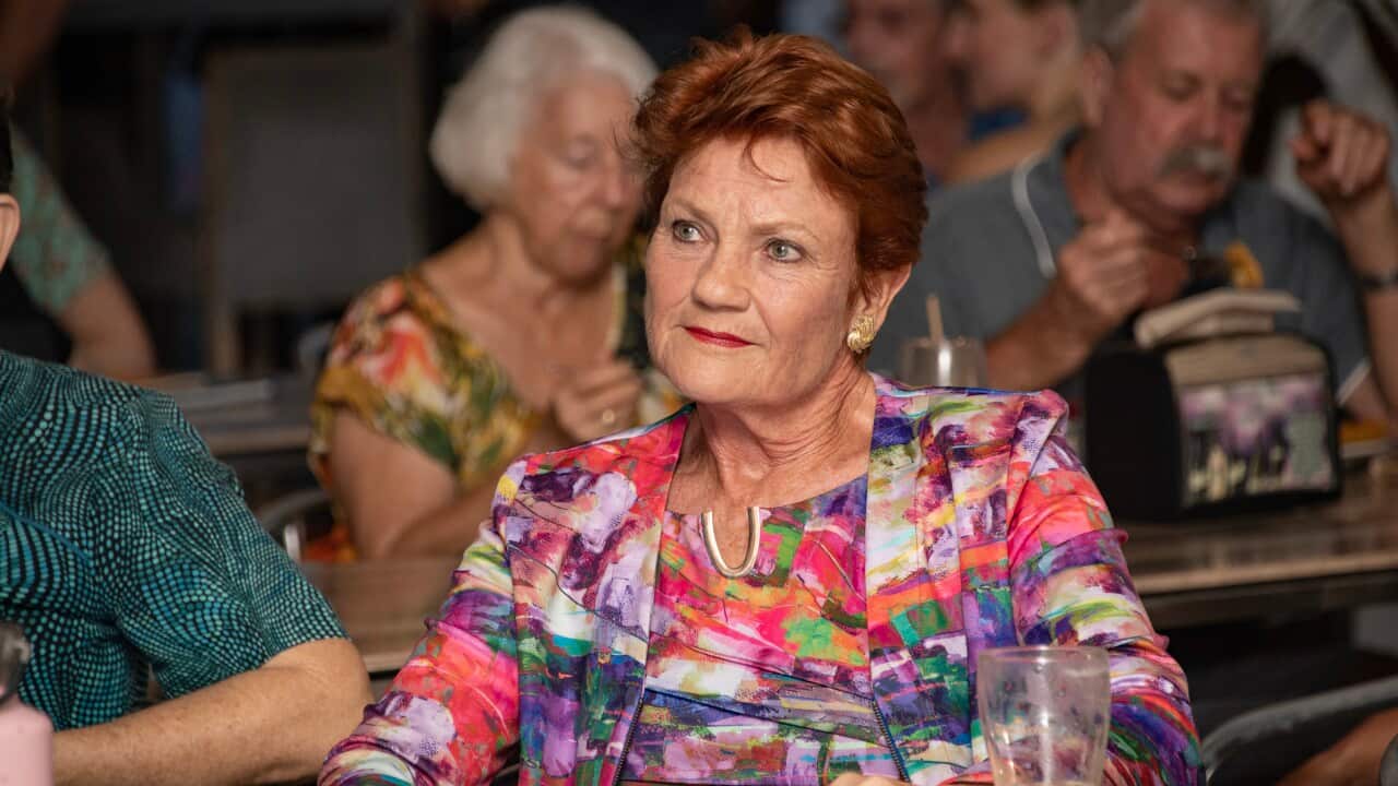 A woman wearing a colourful shirt sits at a table.