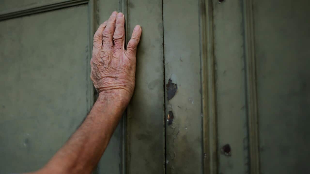 Senior citizen leans against a closed door