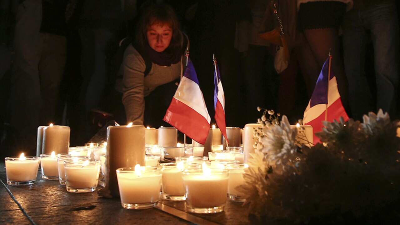 A woman places a candle during a vigil to honor Nice victims