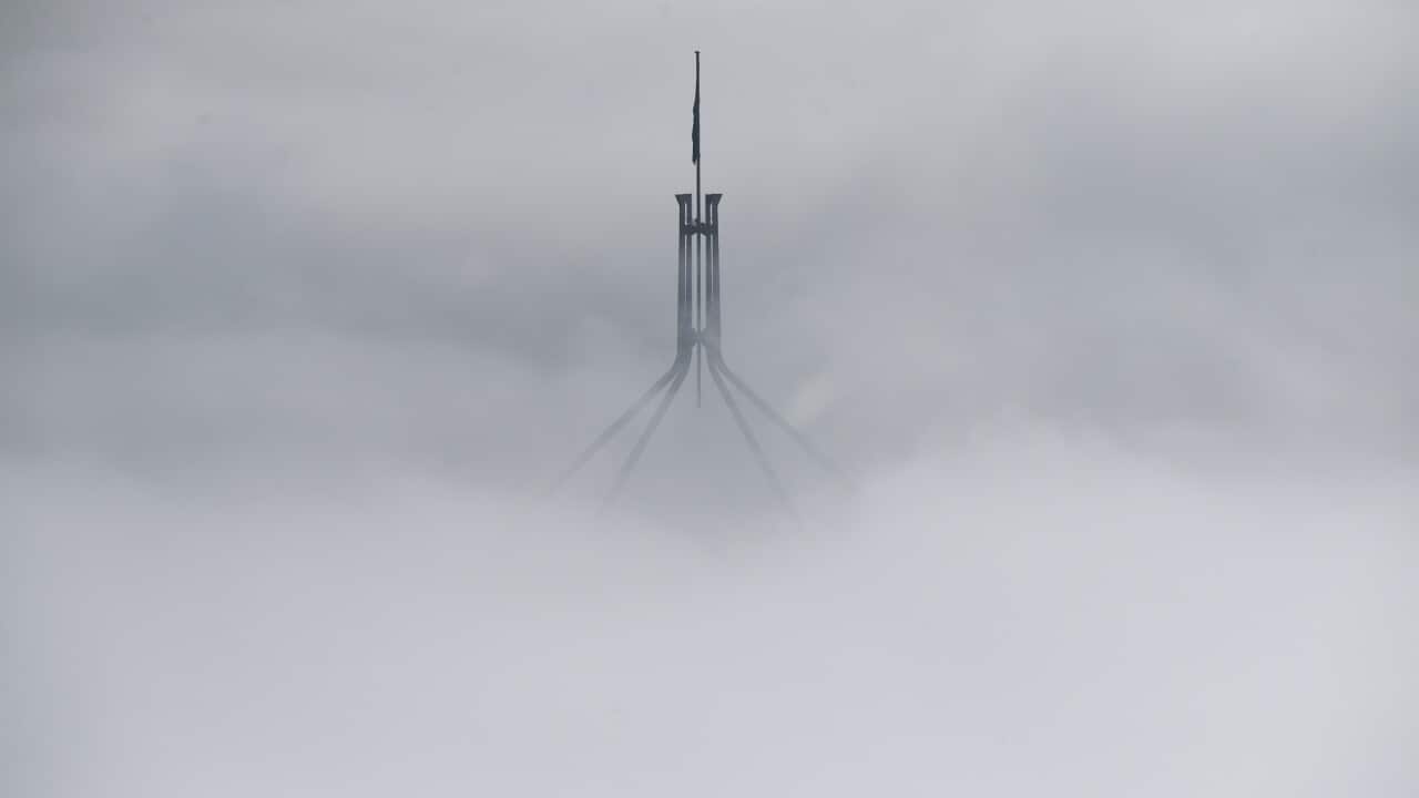 The flag pole of Parliament House in heavy morning fog in Canberra