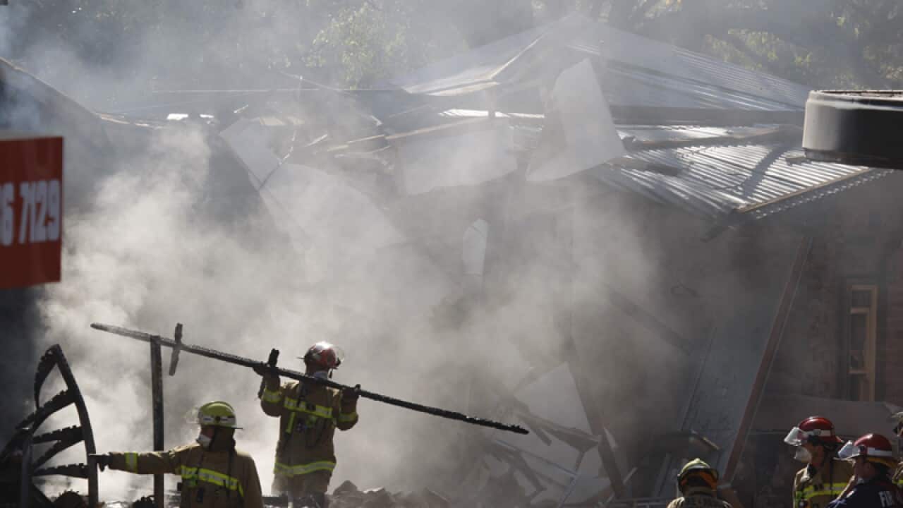 Fire crews sift through the remains of a building in Sydney's west