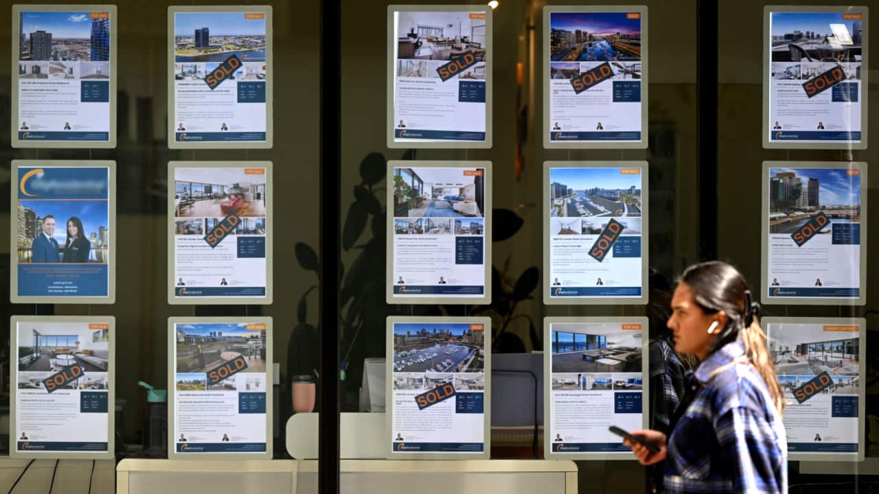A pedestrian walks past a real estate agent's window in Melbourne.