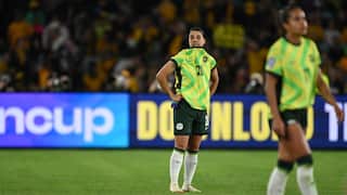 Two football players stand on the pitch wearing yellow and green jerseys
