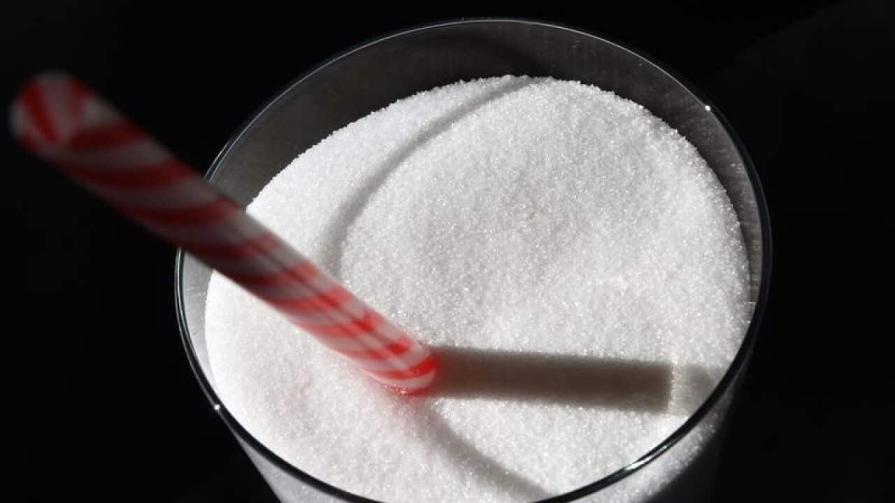 Image of white sugar in a glass with a drinking straw.