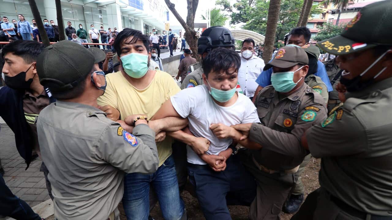 Officers disperse refugees trying to stay overnight outside the UNHCR offices in Medan, Indonesia