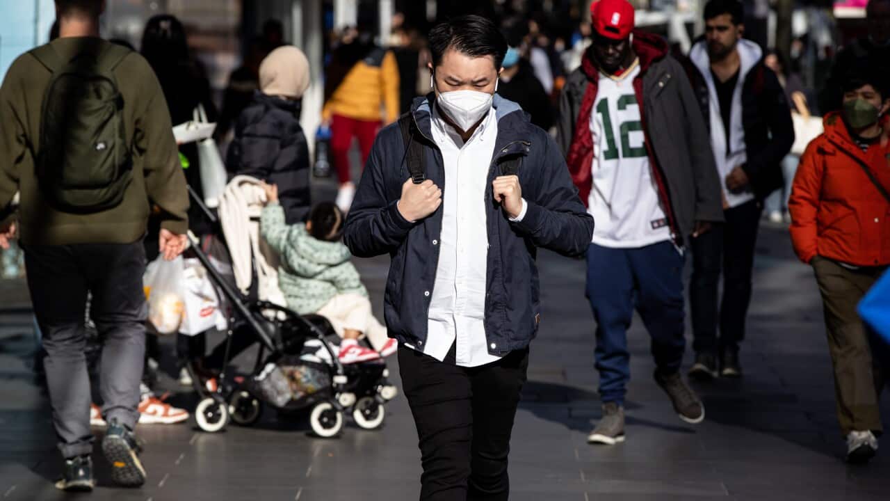 A man wearing a face mask walking down the street