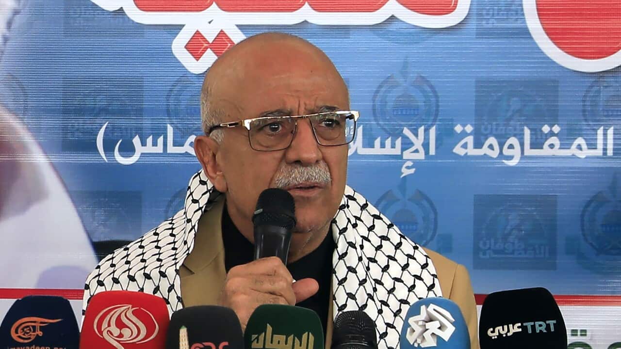 A man gives a speech in front of several microphones.