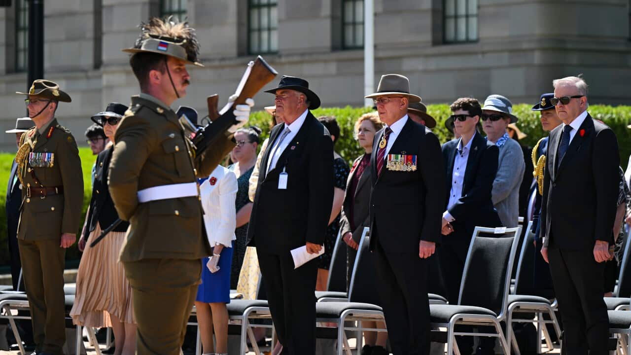 An Australian soldier stands in front of a crowd at a memorial service