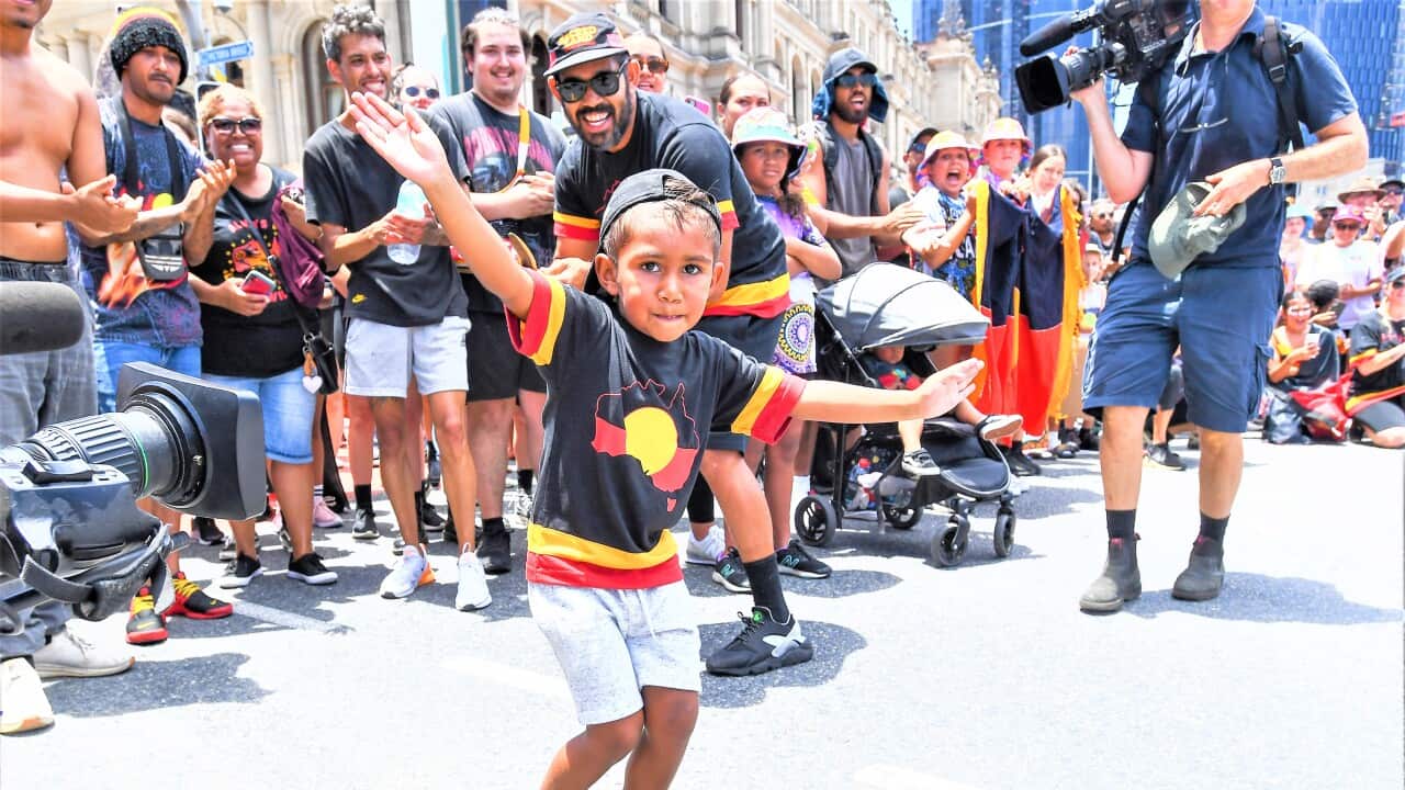 A young boy dances as people march during an Invasion Day rally in Brisbane, Thursday, January 26, 2023 / AAP Image/Jono Searle