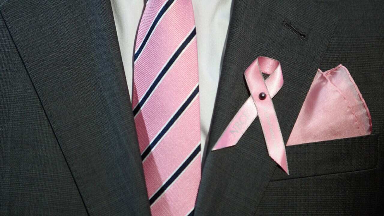 A person wears a pink ribbon in support of breast cancer