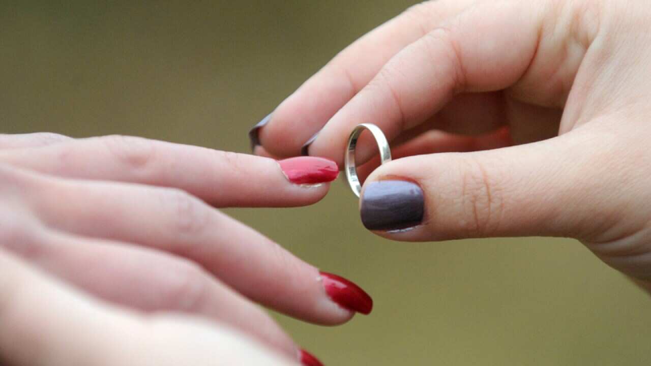 A woman places a wedding ring on her partners finger