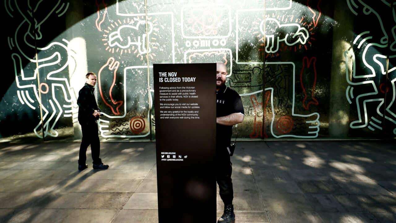 A man places a closed sign out the NGV on March 16, 2020 in Melbourne, Australia. Victorian cultural spaces will close temporarily to the public from today.