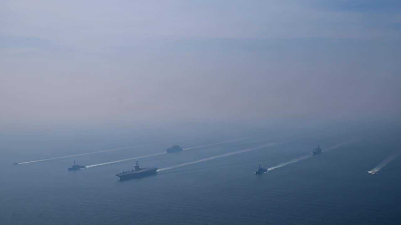 Naval warships sailing in formation in the ocean.