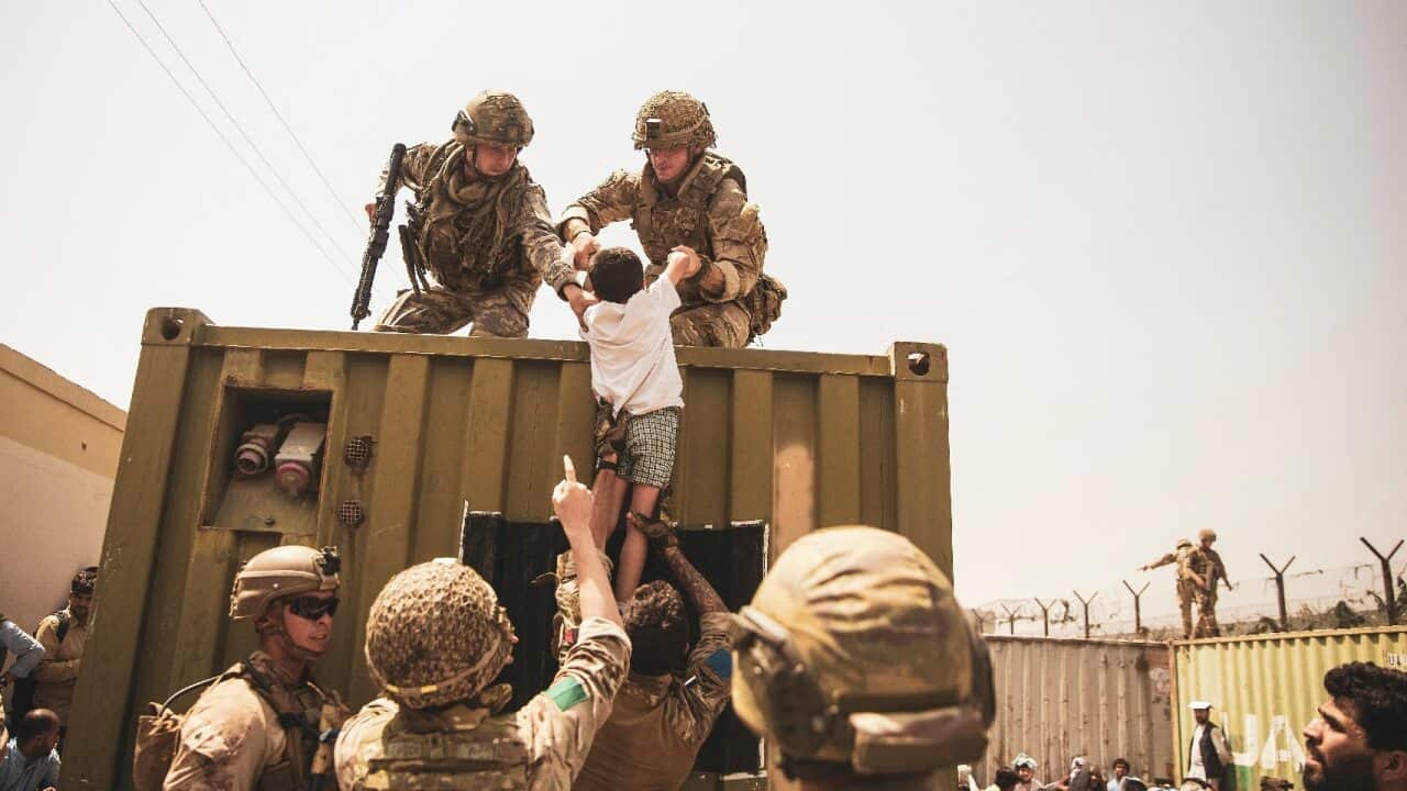 UK coalition forces, Turkish coalition forces, and US Marines assist a child during an evacuation at Hamid Karzai International Airport on 20 August 2021.