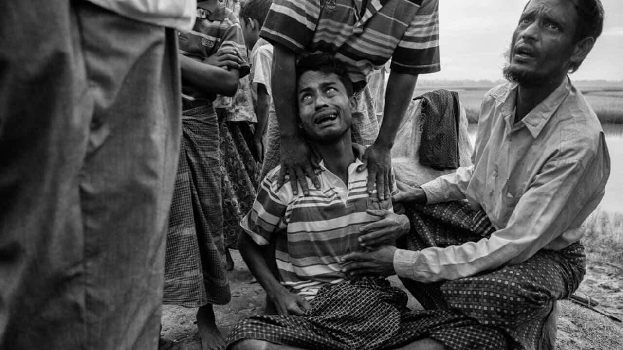 A Rohingya Muslim refugee who had not eaten in several days and was overcome by stomach pains cries as he is helped by a relative