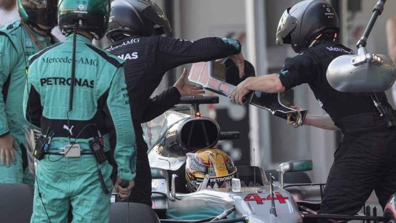 Mechanics change the headrest piece of F1 driver Lewis Hamilton