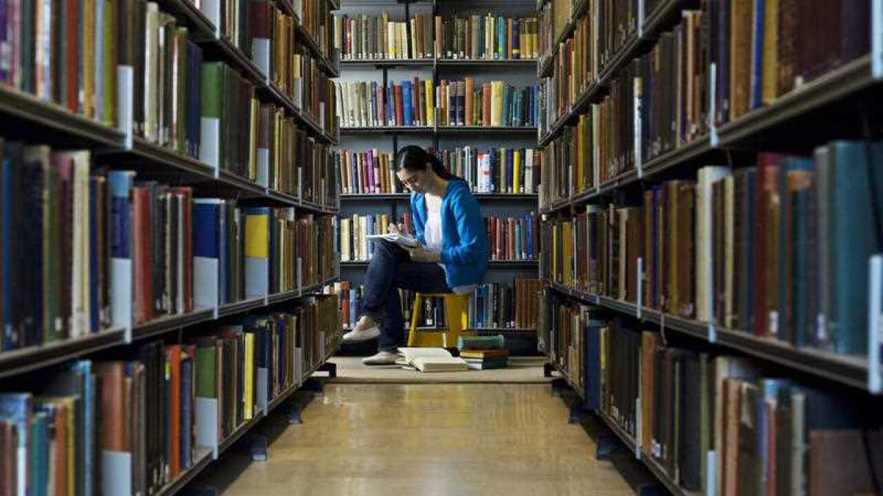 A young woman reads a book in a library