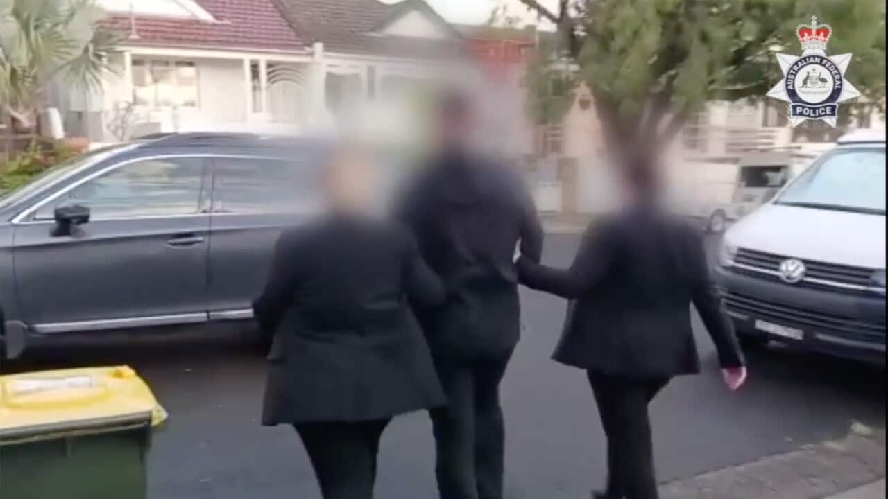 A blurred image of three people walking toward a car with their backs to the camera.