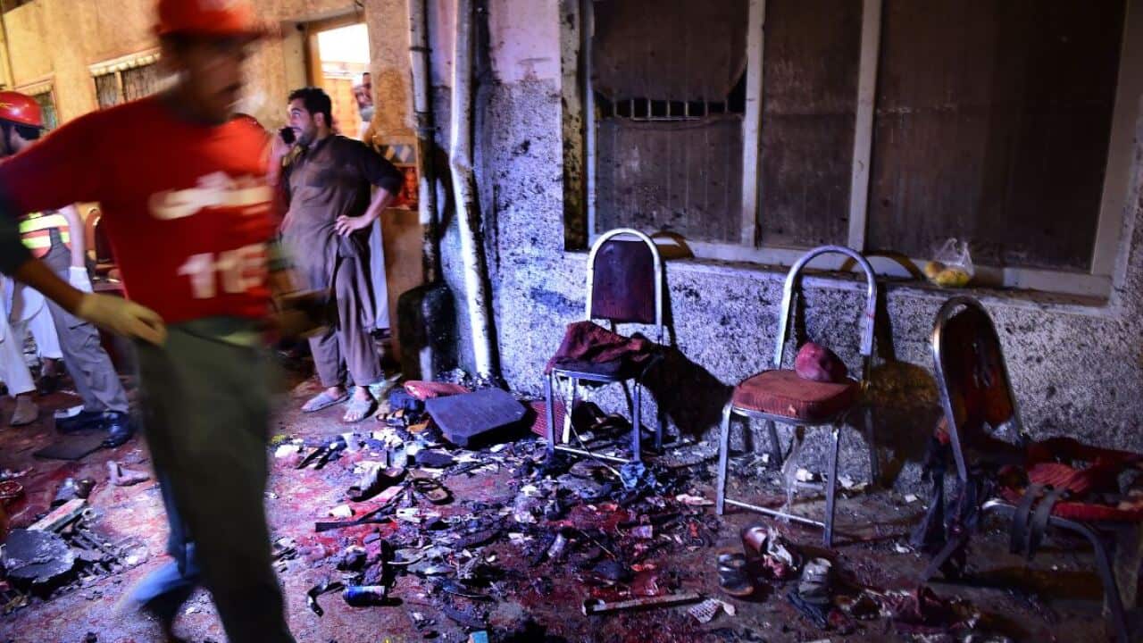 Pakistani security officials and volunteers search the site after a suicide bombing at an election rally in Peshawar on July 10, 2018.