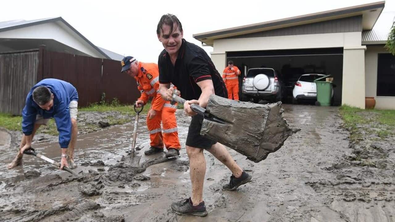 Andrew Hodgson cleans mud off his driveway in Townsville
