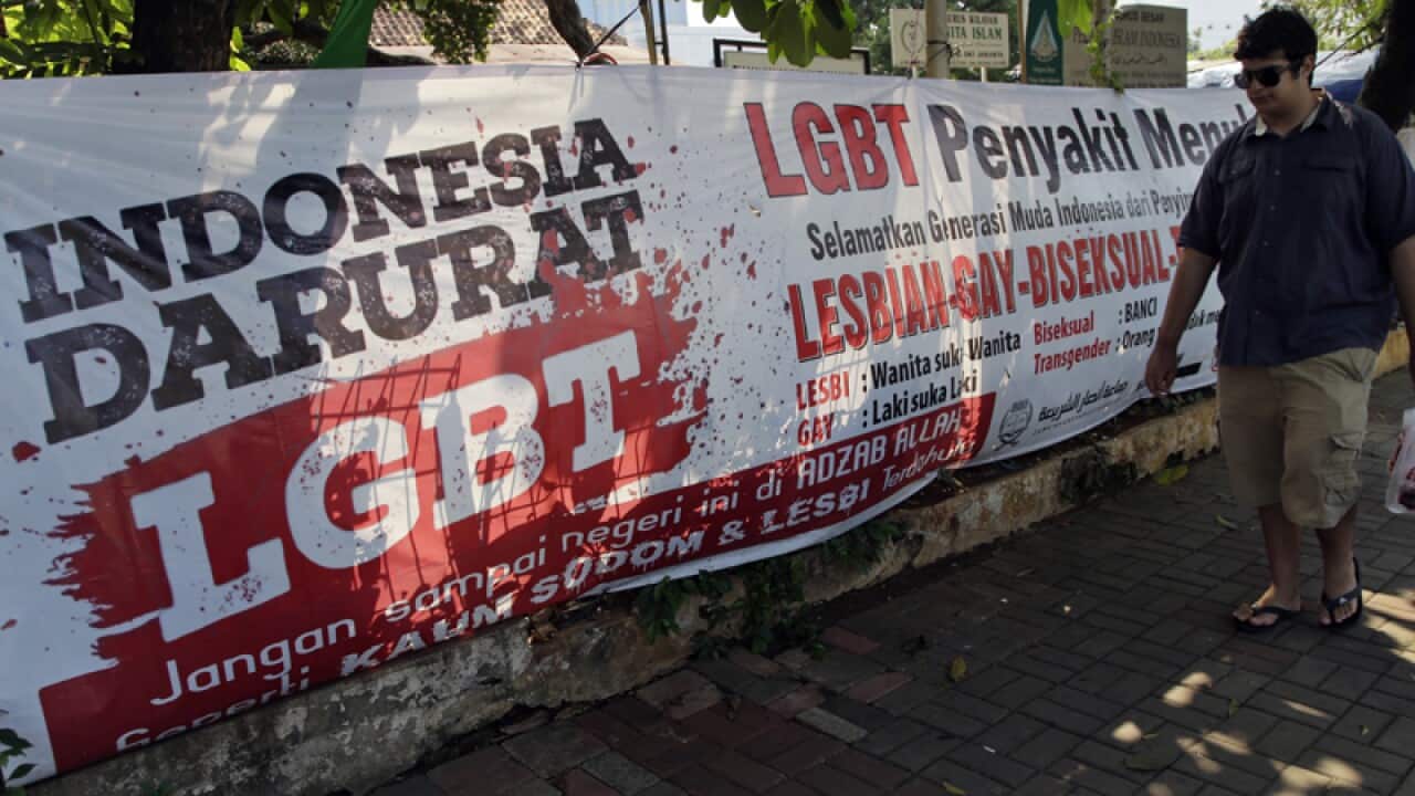 A man walks past an anti-LGBT banner in Jakarta
